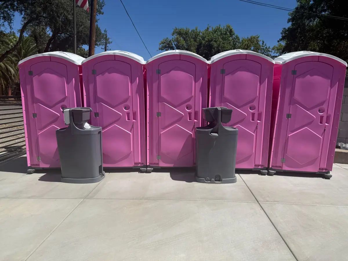 Five pink porta potties with two handwashing stations